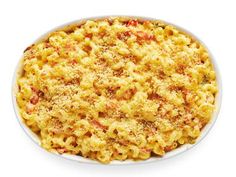 macaroni and cheese in a white dish on a white background with red pepper sprinkles