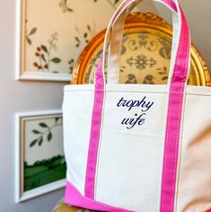 a pink and white tote bag sitting on top of a chair next to pictures