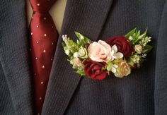 a man wearing a suit and tie with flowers on it's lapel pin