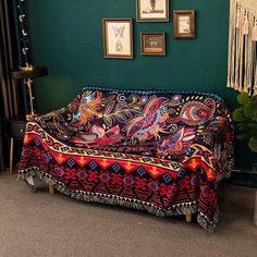 a living room with a couch covered in a colorful blanket and pictures on the wall