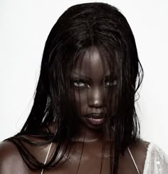 a woman with dark skin and black makeup is posing for the camera, her hair blowing in the wind