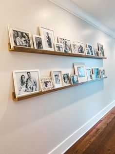 two wooden shelves filled with pictures on the wall next to a wood floor and white walls