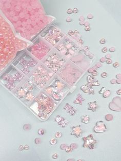 a box filled with lots of pink and white beads next to other items on a table