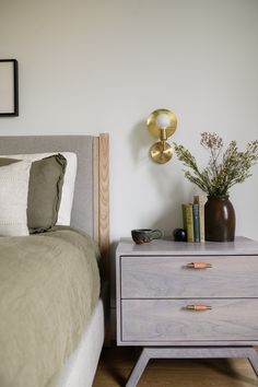 a bedroom with a bed, two nightstands and a plant on the end table