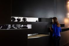 a woman standing next to a wall with pictures on it