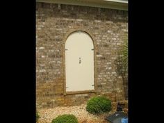 a brick building with a white door and window in the middle of it's front yard