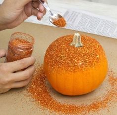 someone is decorating an orange pumpkin with glitter