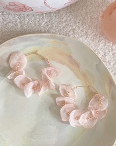 two pink flowers on a plate next to a vase