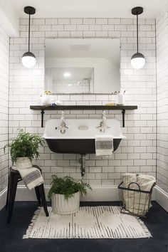 a white tiled bathroom with black and white accessories on the sink, rugs and mirror