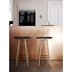 two stools sitting next to each other in front of a gold wall and white door