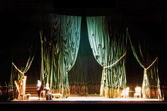 the stage is lit up with green drapes on it's sides and two people sitting in chairs at the end