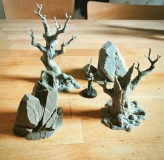 two miniature trees on a wooden table next to rocks and a chess board game piece