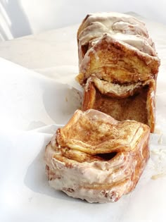 two pastries sitting on top of each other covered in icing and powdered sugar