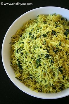 a white bowl filled with yellow rice and spinach sprinkled on top of it