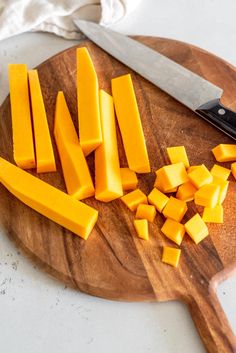 a cutting board topped with sliced cheese next to a knife