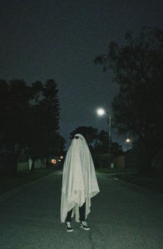 a person dressed as a ghost walking down the street at night