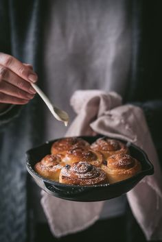 a person holding a pan filled with pastries