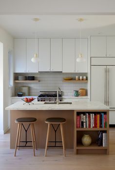 two stools sit in front of an island with bookshelves on the side