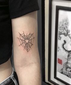 a spider web tattoo on the left arm