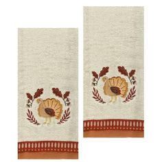 two towels with embroidered turkeys on them and leaves around the edges, one is white