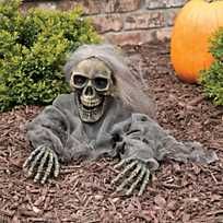 a skeleton sitting on the ground in front of some bushes and plants with fake hands