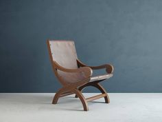 a wooden chair sitting on top of a white floor next to a blue wall in an empty room