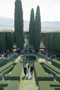 a bride and groom are walking through the mazed hedges in front of an outdoor ceremony