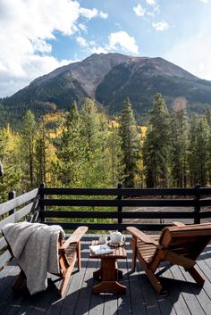 two wooden chairs sitting on top of a wooden deck next to a table and chair