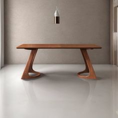 a wooden table sitting on top of a white floor next to a window with a light hanging from it