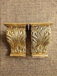 two golden metal vases sitting on top of a carpet