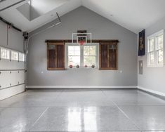 an empty basketball court in the middle of a room with two windows on each side