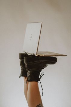 a woman's legs with black leather boots holding a laptop