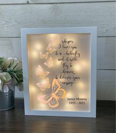 a white frame with butterflies on it next to a potted plant and some flowers