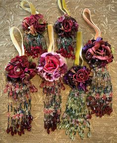 several different types of flowers are arranged on a table top with ribbons and beads hanging from them