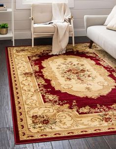 a living room area with a couch, chair and rug on the floor in front of a window