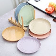 four different colored plates sitting on top of a table next to a knife and fork