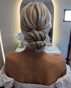 a woman with blonde hair in a white dress is looking at her reflection in the mirror