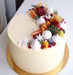 a white cake topped with fruit on top of a gold plated serving platter