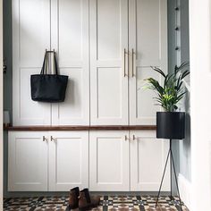 a pair of shoes sitting on top of a tiled floor next to a potted plant