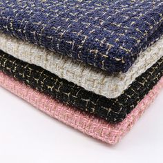 four different colors of tweed fabric stacked on top of each other, one pink and one blue