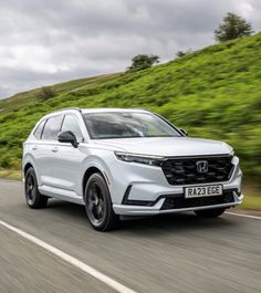 a white honda suv driving down the road