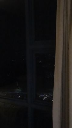 a window with a view of the city lights at night from it's side