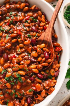 a white bowl filled with beans and garnished with parsley on the side