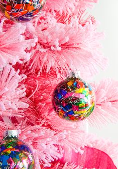 a pink christmas tree with ornaments hanging from it's branches and colorful tinsel