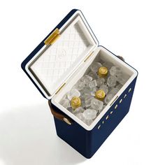 an open blue box with ice cubes in it on a white surface and gold trimming around the lid