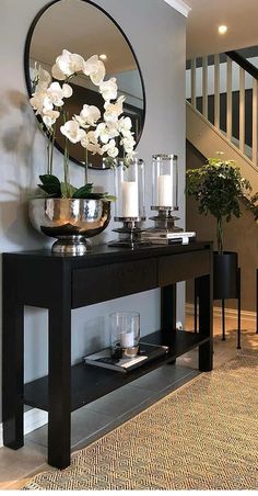 a black table with flowers and candles on it in front of a stair case next to a mirror