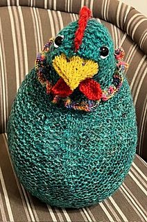 a knitted bird sitting on top of a chair next to a striped wallpaper