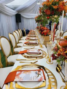 a long table set with place settings and flowers