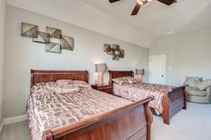 two beds in a bedroom with white walls and ceiling fan above the bed, along with other furniture