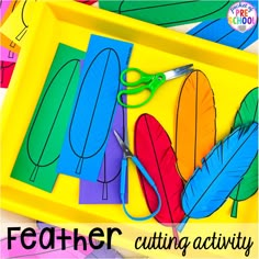 a yellow tray with scissors and paper cut outs on it that says feather cutting activity